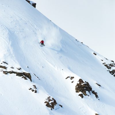 A vertical shot of a male skiing on the mountain covered with snow in winter